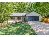 Charming single-story home features a well-kept lawn, covered porch, and two-car garage nestled among mature trees at 2020 Commonwealth Pl, Cumming, GA 30041