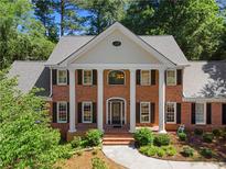 Stately two-story brick home featuring a columned entryway, black shutters, and mature landscaping at 2595 Winthrope Way, Lawrenceville, GA 30044