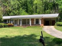 Charming brick home featuring a covered porch, large windows, and a well-manicured front yard at 2703 Arrowood Dr, East Point, GA 30344