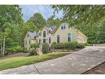 Beautiful home with mature landscaping, multiple windows and an attached two-car garage at 5940 Plantation Dr, Roswell, GA 30075