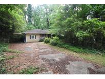 Quaint one-story home nestled among lush trees with a covered carport and driveway at 1847 Colt Dr, Brookhaven, GA 30341