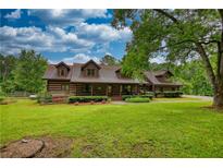 Charming log home featuring a well-manicured lawn, inviting porch, and lush landscaping at 2905 Cammie Wages Rd, Dacula, GA 30019