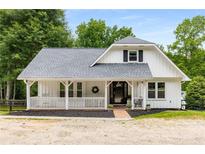 Charming white farmhouse with a covered porch and well-manicured landscaping at 999 Bailey Rd, Woodstock, GA 30188