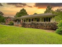 Inviting single-story home featuring a cozy front porch, manicured lawn, and lush, mature landscaping at 78 N Pomona Rd, Hampton, GA 30228