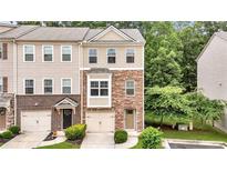 Charming townhome featuring a stone facade, attached garage, and well-maintained landscaping at 893 Society Sw Cir, Atlanta, GA 30331