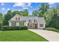 Charming home with a manicured lawn, mature trees, and a welcoming facade at 6890 Autumn Hills Dr, Cumming, GA 30028