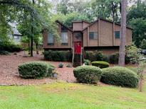 Charming home featuring a red front door, mature trees, and lush landscaping at 317 Hoofbeat Ne Trl, Kennesaw, GA 30144