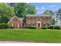 Beautiful two-story brick home with a manicured green lawn and mature trees at 6165 Pin Oak Ln, Alpharetta, GA 30005