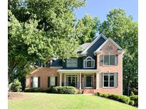 Charming two-story brick home with a lush front yard, mature trees, and a welcoming facade at 2073 Woodside Park Dr, Woodstock, GA 30188