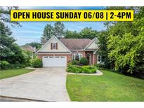 Charming brick home with a manicured lawn, mature trees, and a welcoming two-car garage at 635 Piping Rock Pt, Lawrenceville, GA 30043