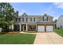 Charming two-story home with a well-manicured lawn, stone accents, and a two-car garage at 143 Monarch Way, Hiram, GA 30141