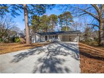 Charming renovated home with carport, white siding, dark shutters, and fresh landscaping at 1890 Carla Dr, Morrow, GA 30260