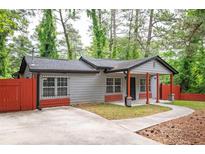 Charming gray home featuring a red fence and complementary red porch posts, complete with a freshly paved driveway at 3479 Thompson Dr, Atlanta, GA 30331