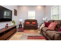 Inviting living room with brown couches, large windows, and a colorful area rug at 3479 Thompson Dr, Atlanta, GA 30331