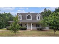 Charming home featuring a covered front porch, dormer windows, and mature landscaping at 385 Eagles Nest Cir, Carrollton, GA 30116