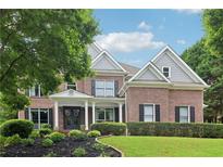Charming two-story brick home with a landscaped front yard, dark shutters, and a welcoming covered porch entry at 4085 Hillcrest View Ct, Suwanee, GA 30024