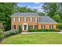 Charming brick home featuring a well-manicured lawn, neat landscaping, and classic colonial architecture at 5524 Wedgewood Sw Ct, Lilburn, GA 30047