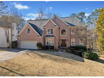 Charming two-story brick home with a well-manicured front lawn and attached two-car garage at 735 Amberton Close, Suwanee, GA 30024