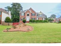 Traditional brick home with manicured lawn, dark shutters, and well-maintained landscaping at 930 Cedar Bluff Sw Trl, Lilburn, GA 30047