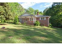 Charming brick home with a welcoming screened-in porch and lush, green lawn at 5670 Lanny Dr, Powder Springs, GA 30127