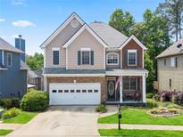 Charming two-story home with brick accents, white garage door, front porch, and a well-maintained lawn at 180 Mirramont Lake Dr, Woodstock, GA 30189