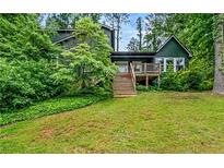 Charming two-story home with a wooden deck and stairs, surrounded by lush green landscaping at 1033 Justice Nw Ln, Acworth, GA 30102