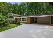 Charming exterior elevation with a brick facade, carport, and a well-manicured lawn with mature trees at 225 River Springs Dr, Sandy Springs, GA 30328