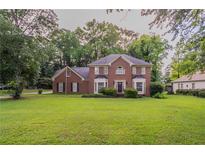 Charming two-story brick home with a manicured lawn and mature trees at 214 Jamestown Ave, Jonesboro, GA 30236