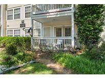 Inviting condo exterior featuring a covered porch, white railing, and lush landscaping, perfect for relaxing outdoors at 1364 Keys Crossing Ne Dr, Atlanta, GA 30319