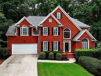 Two-story brick home with a two-car garage, manicured lawn and mature trees at 1850 Noblin Ridge Way, Duluth, GA 30097