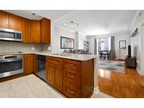 Modern kitchen with stainless steel appliances, wood cabinets, and granite countertops open to the living area at 1101 Juniper Ne St # 1216, Atlanta, GA 30309