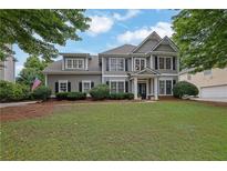 Beautiful two-story home with manicured lawn, mature trees, and a traditional facade with black shutters at 4218 Sandy Branch Dr, Buford, GA 30519