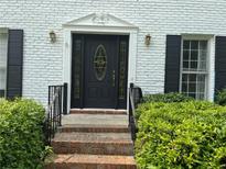 Charming front door with decorative glass and brick steps, framed by lush green bushes at 1159 Aurora Ct, Atlanta, GA 30338