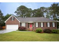 Charming single-story brick home with a well-manicured lawn and a bright red front door at 2884 Overwood Ln, Snellville, GA 30078