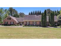Charming brick home with a well-maintained lawn and mature trees under a clear sky at 1935 Northbrooke Ln, Dunwoody, GA 30338