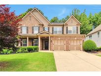 Beautiful two-story home with brick and siding, a well-manicured lawn, and a three-car garage at 5613 Lancashire Ln, Cumming, GA 30041