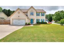 Charming two-story home featuring a lush green lawn and a lovely teal-blue front door and matching shutters at 2995 Belshire Trl, Dacula, GA 30019