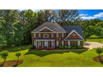 Beautiful two-story brick home featuring a manicured lawn and mature trees at 125 Legacy Way, Oxford, GA 30054
