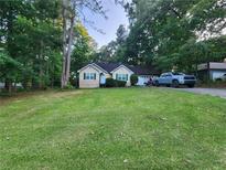Quaint home featuring green lawn, mature trees, complementary green trim, and an attached two-car garage at 273 Apalachee Church Rd, Auburn, GA 30011
