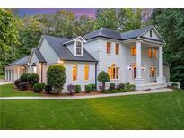 Elegant white brick home featuring a manicured lawn and lush landscaping at 5145 Saddlebred Ln, Cumming, GA 30028