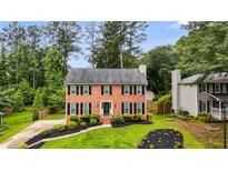 Charming two-story brick home boasts lush landscaping, a well-manicured lawn, and classic black shutters at 225 Carriage Station Cir, Roswell, GA 30075