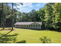 Charming ranch-style home with a large front yard and covered front porch surrounded by mature trees at 6133 Post Rd, Douglasville, GA 30135