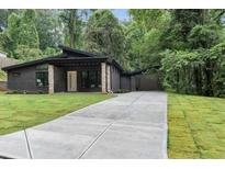 Charming one-story home featuring dark brick, modern design, and a long driveway leading to an attached garage at 998 Lookout Nw Ave, Atlanta, GA 30318