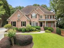 Charming two-story brick home featuring a well-manicured lawn and mature landscaping at 10135 High Falls Pointe, Johns Creek, GA 30022