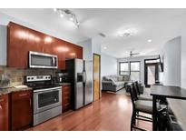 Modern kitchen featuring stainless steel appliances and rich wood cabinetry, seamlessly flowing into the living area at 898 Oak Sw St # 3204, Atlanta, GA 30310