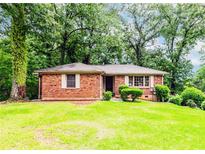 Charming brick home featuring a lush green lawn and mature trees providing ample shade and curb appeal at 1913 Flintwood Se Dr, Atlanta, GA 30316