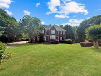 Charming two-story brick home boasts a lush green lawn and mature trees, offering great curb appeal at 209 Breckenridge Ct, Canton, GA 30115