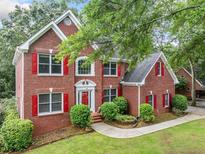 Two-story brick home with red shutters, green lawn, mature trees, and an inviting front entrance at 5190 Beech Forest Sw Dr, Lilburn, GA 30047