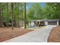 Charming home with a long driveway and a beautifully landscaped front yard surrounded by mature trees at 3455 Broxton Mill Way, Snellville, GA 30039