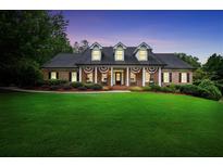 Charming brick home featuring a well-manicured lawn and classic colonial-style architecture at dusk at 704 Branchview Ct, Mcdonough, GA 30252